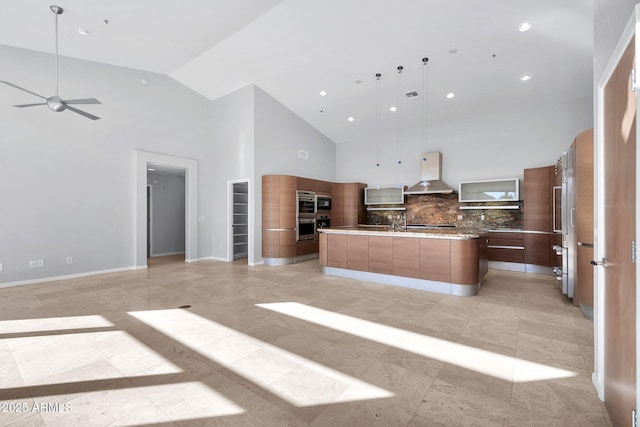 kitchen with pendant lighting, high vaulted ceiling, decorative backsplash, wall chimney exhaust hood, and a spacious island