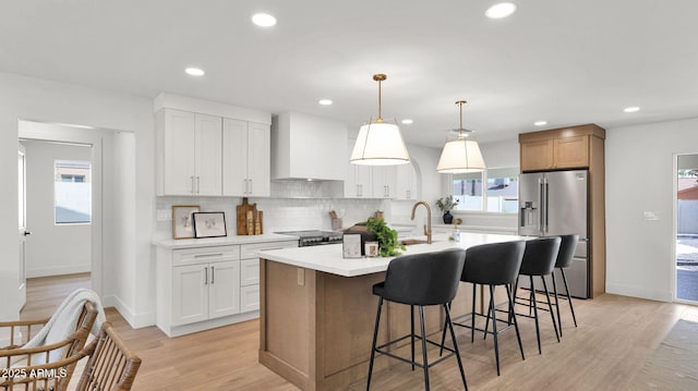 5109 E Blanche Dr, Scottsdale, AZ 85254 - kitchen featuring high end refrigerator, wall chimney range hood, a center island with sink, tasteful backsplash, and light countertops