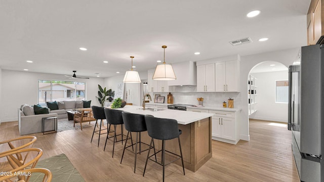 5109 E Blanche Dr, Scottsdale, AZ 85254 - kitchen featuring premium range hood, arched walkways, light countertops, a breakfast bar area, and appliances with stainless steel finishes