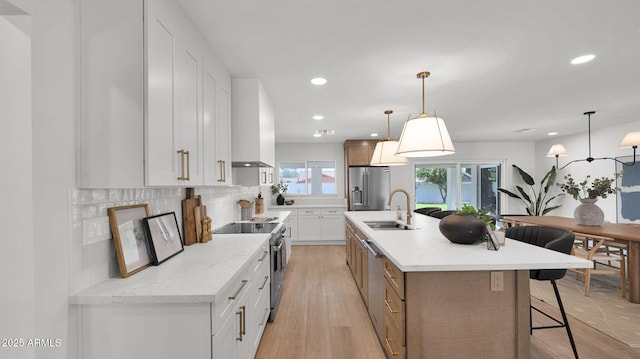 5109 E Blanche Dr, Scottsdale, AZ 85254 - kitchen featuring stainless steel appliances, a sink, wall chimney exhaust hood, tasteful backsplash, and a kitchen bar