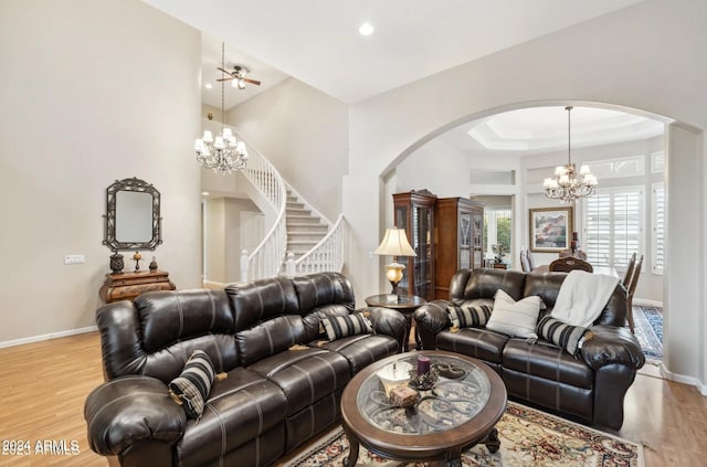 living room with a raised ceiling, light hardwood / wood-style flooring, and a chandelier