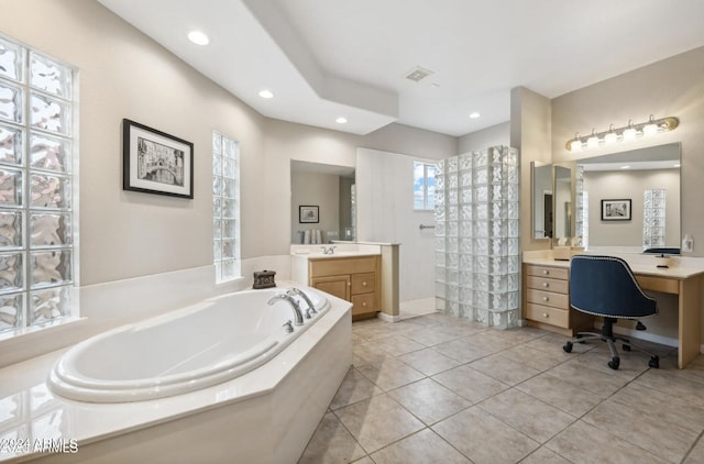 bathroom with tiled tub, vanity, and tile patterned floors