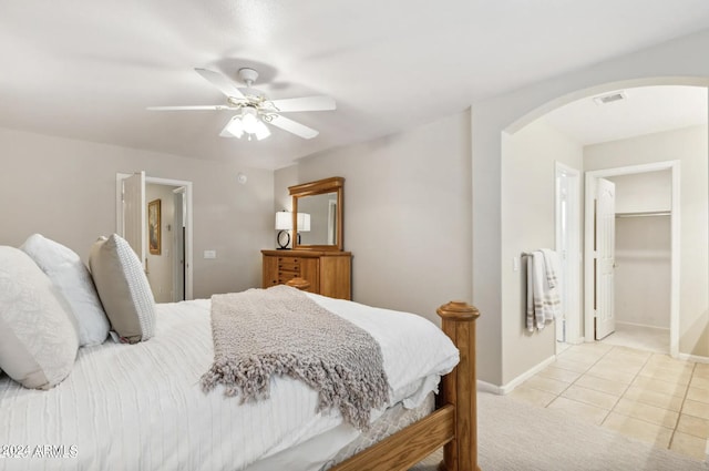 tiled bedroom with ceiling fan, a walk in closet, and a closet