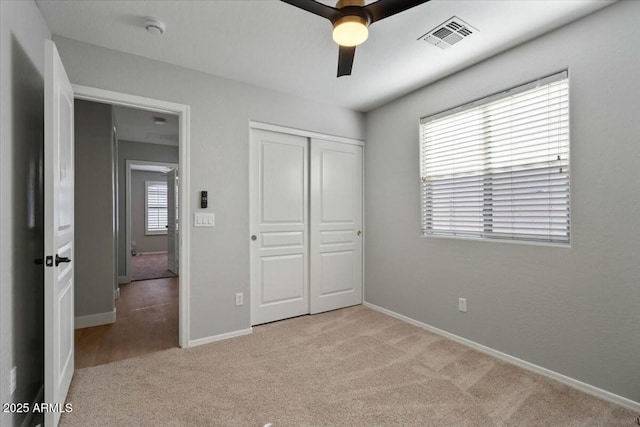 unfurnished bedroom featuring ceiling fan, light colored carpet, and a closet