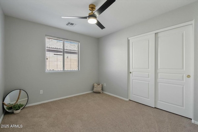 unfurnished bedroom featuring ceiling fan, light colored carpet, and a closet