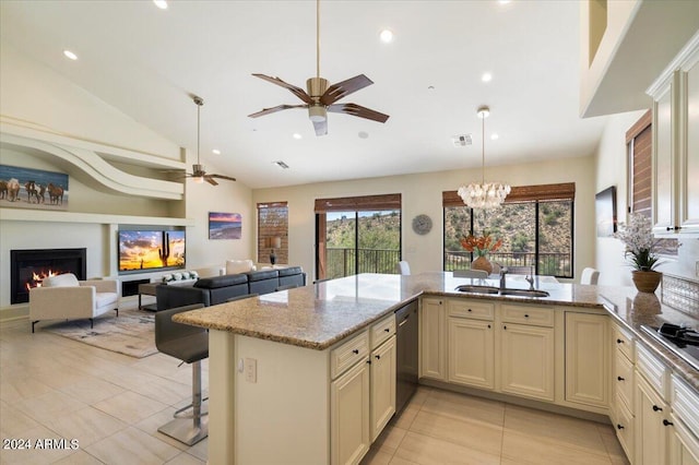 kitchen featuring cream cabinets, sink, pendant lighting, light stone counters, and a breakfast bar area