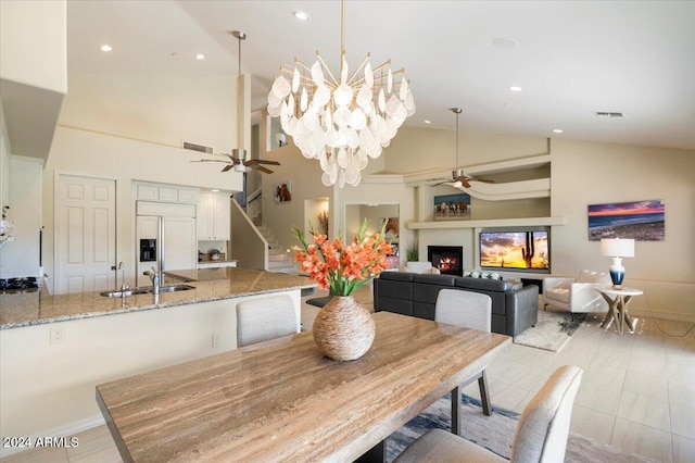 dining room featuring sink, ceiling fan with notable chandelier, and high vaulted ceiling