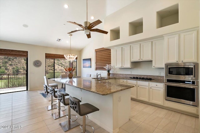 kitchen with hanging light fixtures, appliances with stainless steel finishes, a breakfast bar, dark stone countertops, and sink