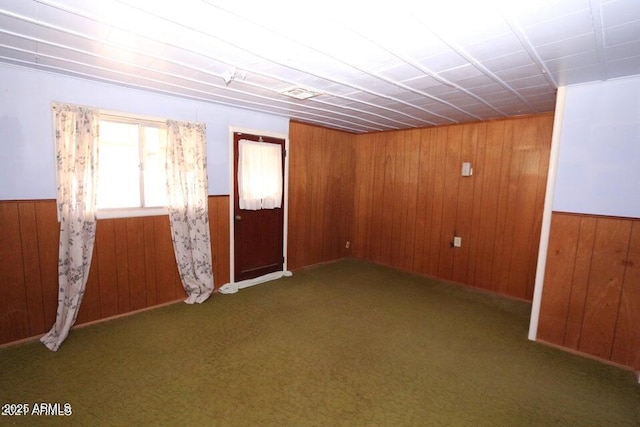 carpeted spare room with wooden walls