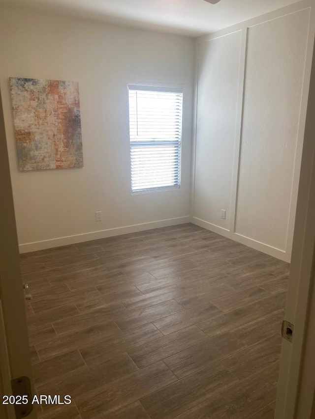 spare room featuring dark wood finished floors and baseboards