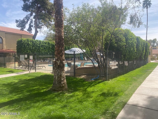 view of community with a yard, a pool, and fence