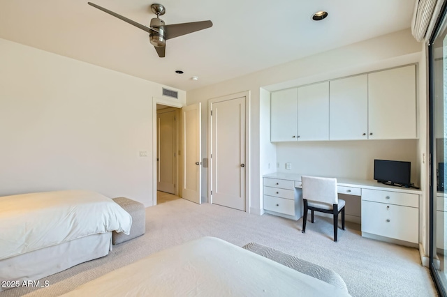 carpeted bedroom featuring built in desk and ceiling fan