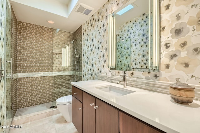 bathroom featuring toilet, tile walls, vanity, a shower with door, and tile patterned flooring