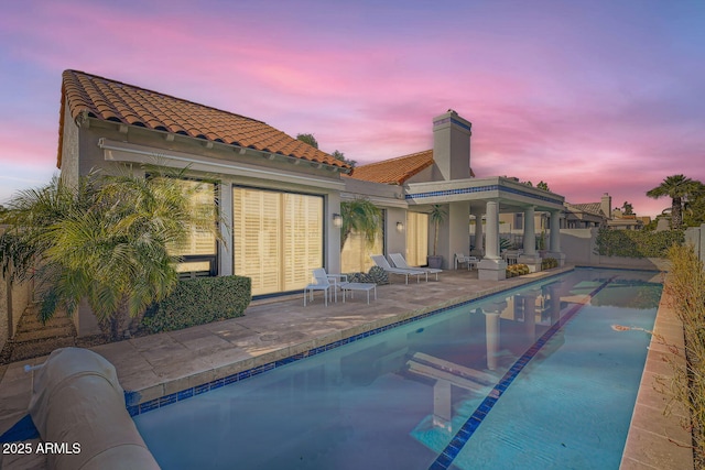 back house at dusk with a patio area