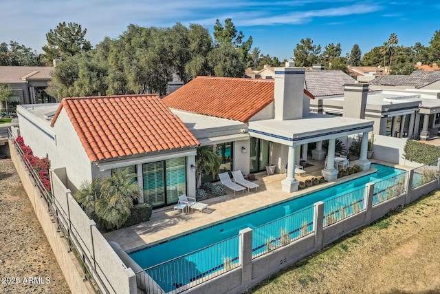 back of property featuring a fenced in pool and a patio area