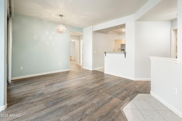 unfurnished room featuring light wood finished floors, baseboards, and an inviting chandelier