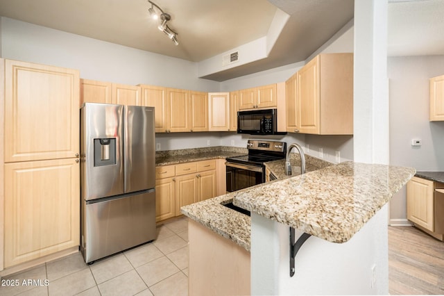 kitchen with light stone counters, visible vents, appliances with stainless steel finishes, light brown cabinets, and a peninsula