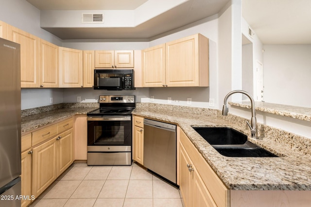 kitchen featuring visible vents, stainless steel appliances, a sink, and light brown cabinetry