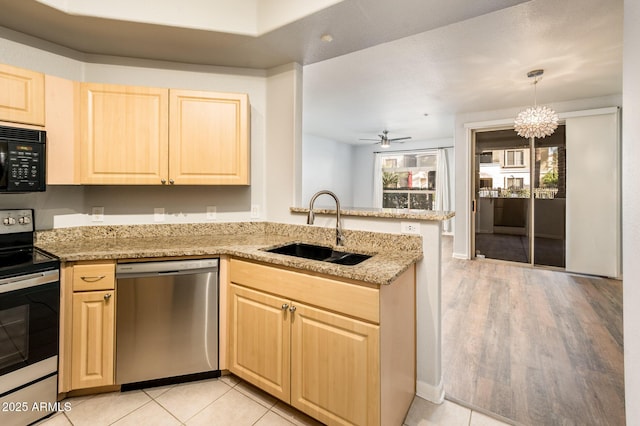 kitchen featuring light stone countertops, appliances with stainless steel finishes, a sink, and light brown cabinetry