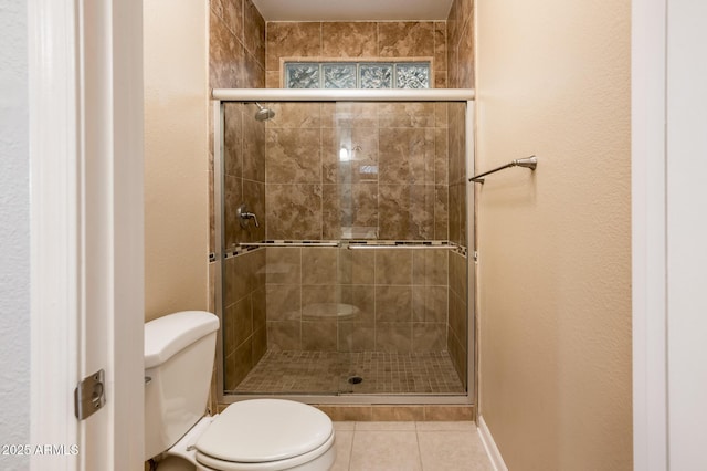 bathroom featuring tile patterned flooring, a shower stall, and toilet