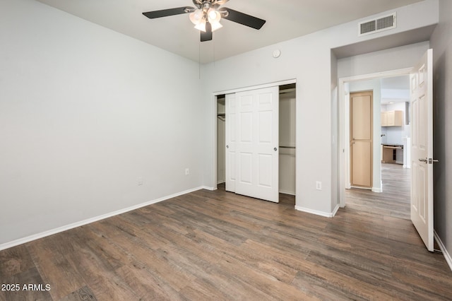 unfurnished bedroom featuring a closet, visible vents, a ceiling fan, wood finished floors, and baseboards