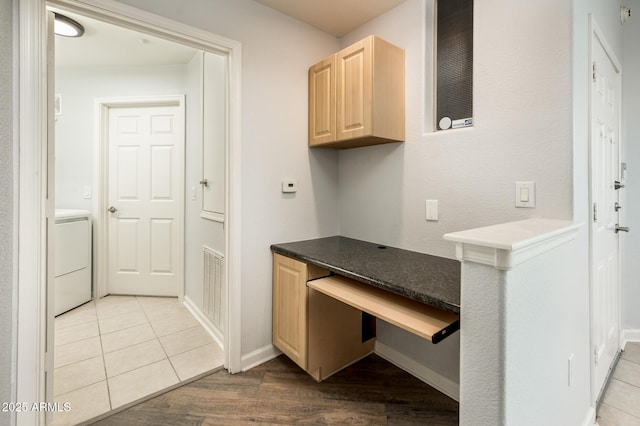 interior space with washer / clothes dryer, visible vents, light brown cabinetry, built in study area, and baseboards