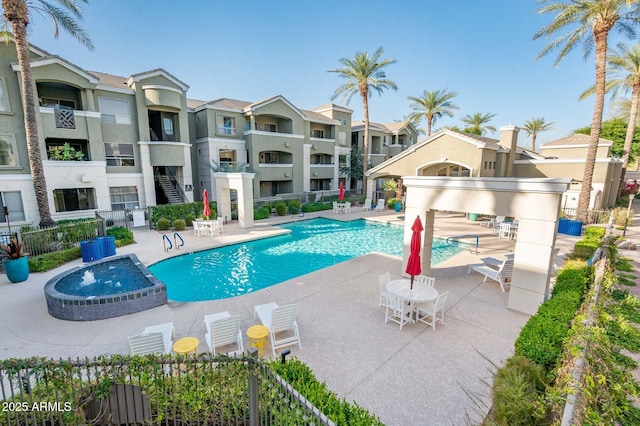 view of swimming pool featuring a patio area, a pool with connected hot tub, and fence