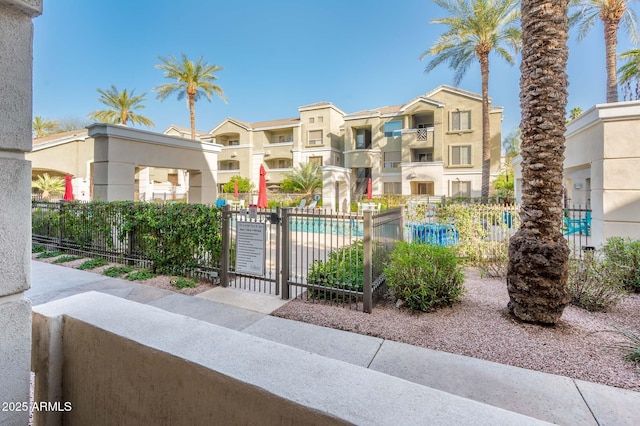 view of front of property featuring a gate, a residential view, fence, and a community pool