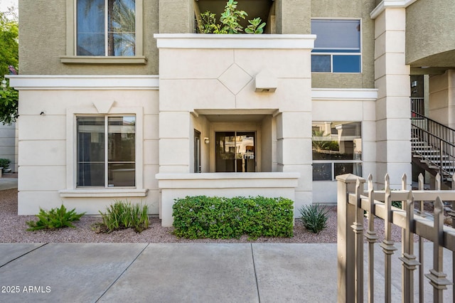 doorway to property with fence and stucco siding