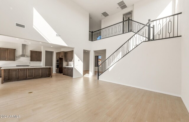 unfurnished living room featuring a towering ceiling and light hardwood / wood-style flooring