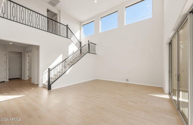 unfurnished living room with a towering ceiling and light hardwood / wood-style floors