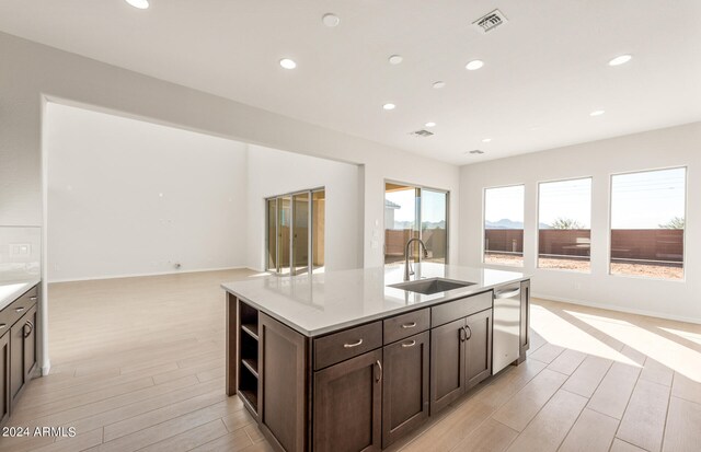 kitchen with an island with sink, light hardwood / wood-style floors, sink, and stainless steel dishwasher