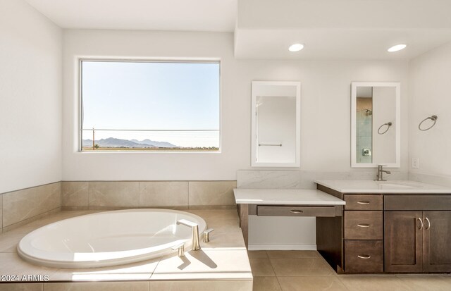 bathroom featuring vanity, a relaxing tiled tub, and tile patterned flooring