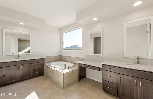 bathroom with tiled bath, tile patterned floors, and vanity