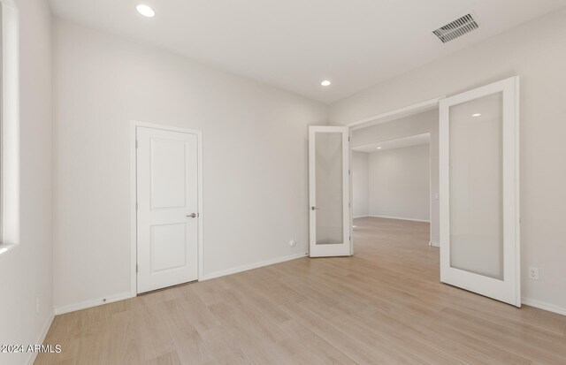 empty room featuring french doors and light hardwood / wood-style floors