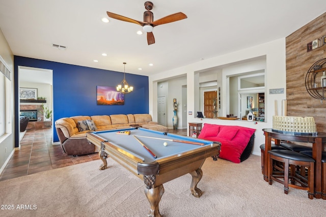 rec room featuring visible vents, carpet, a stone fireplace, ceiling fan with notable chandelier, and billiards
