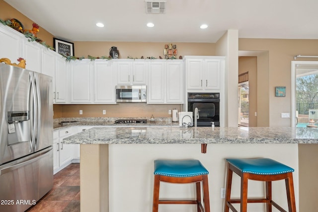 kitchen featuring a breakfast bar, appliances with stainless steel finishes, visible vents, white cabinets, and recessed lighting