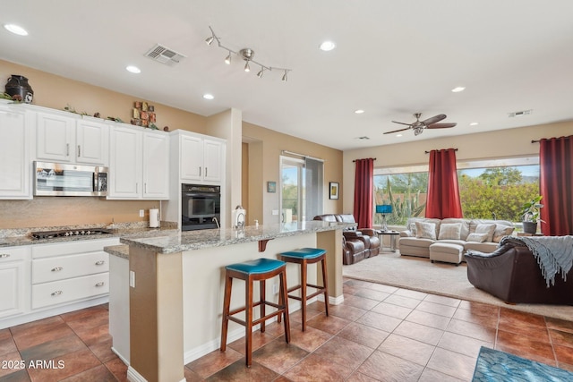 kitchen featuring open floor plan, a kitchen island with sink, appliances with stainless steel finishes, and visible vents