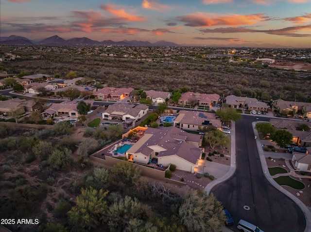 aerial view at dusk featuring a mountain view and a residential view