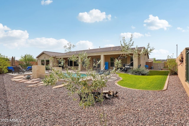 rear view of house featuring a fenced backyard, a tile roof, stucco siding, and a patio area