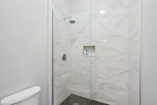 bathroom featuring a textured wall, toilet, and a stall shower