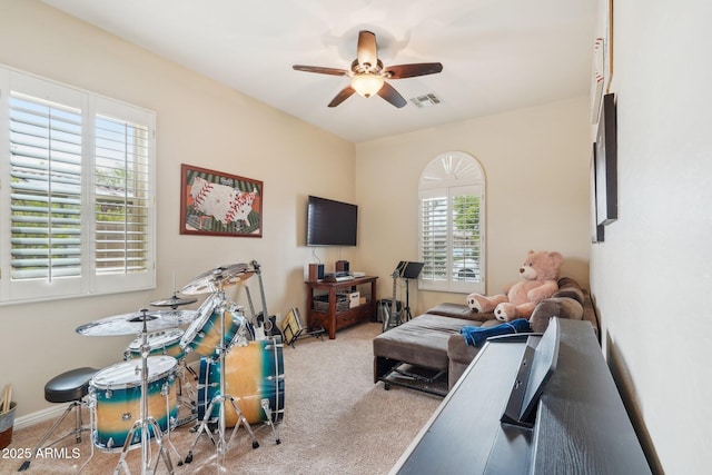 carpeted living area with baseboards, visible vents, and ceiling fan