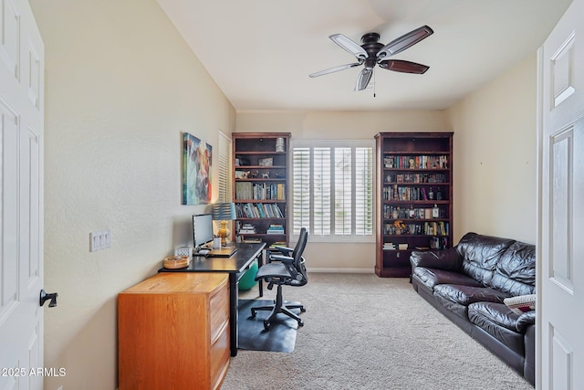 carpeted home office with baseboards and a ceiling fan