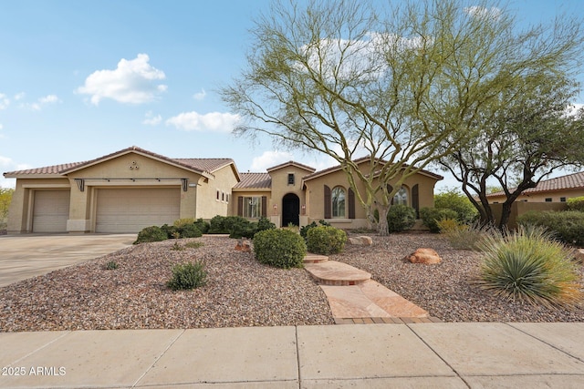 mediterranean / spanish house with a tiled roof, stucco siding, an attached garage, and driveway
