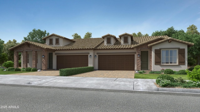 mediterranean / spanish-style home featuring decorative driveway, a garage, stucco siding, and a tiled roof