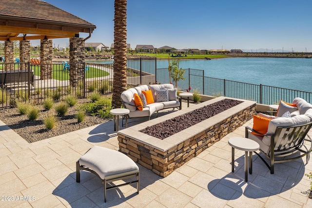 view of patio with a water view, an outdoor living space with a fire pit, and fence