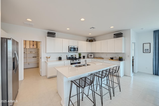 kitchen with visible vents, a sink, stainless steel appliances, a breakfast bar area, and light countertops