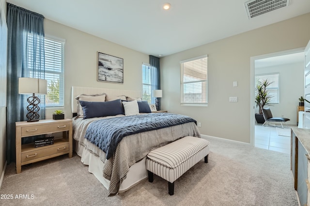 bedroom featuring baseboards, visible vents, and light carpet