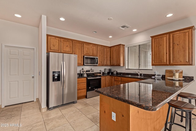 kitchen featuring stainless steel appliances, kitchen peninsula, sink, and dark stone counters