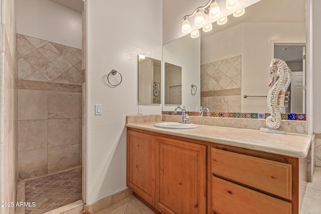 bathroom with vanity, a tile shower, and tile patterned floors